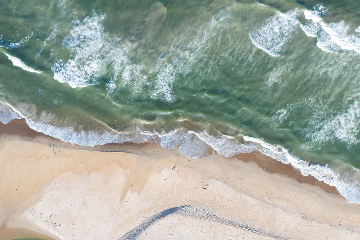 Aerial view of one of the top 10 beaches in Japan with turquoise water, white sand, and lush green cliffs