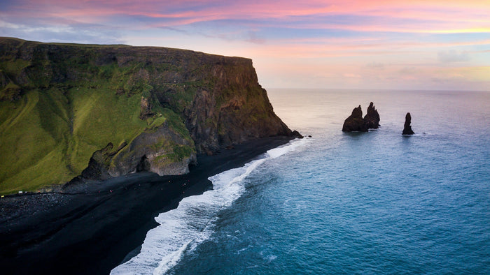 Aerial view of one of the top10 beaches in Iceland with black volcanic sand, cliffs, and arctic blue waters