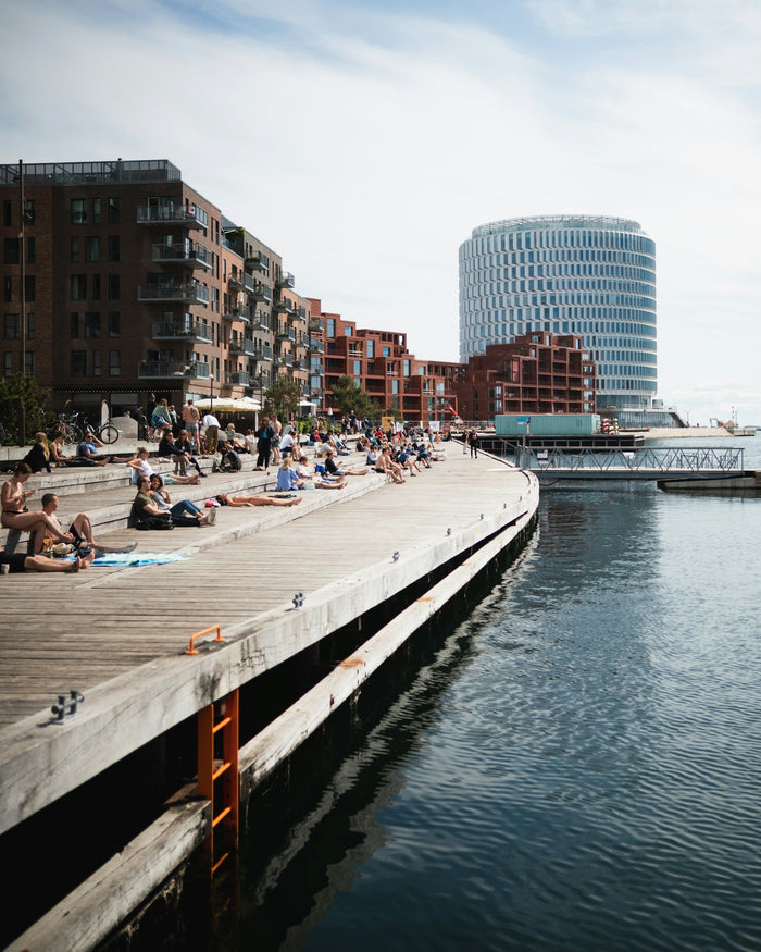 View of a local Copenhagen harbor bath with swimmers jumping in, wooden decks, and modern buildings in the background