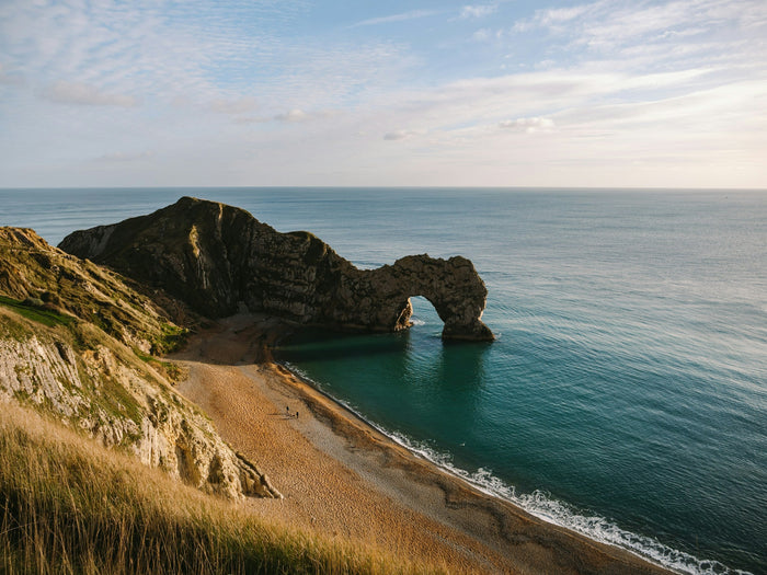Aerial view of one of the top10 beaches in the United Kingdom with golden sand, rugged cliffs, and clear blue sea