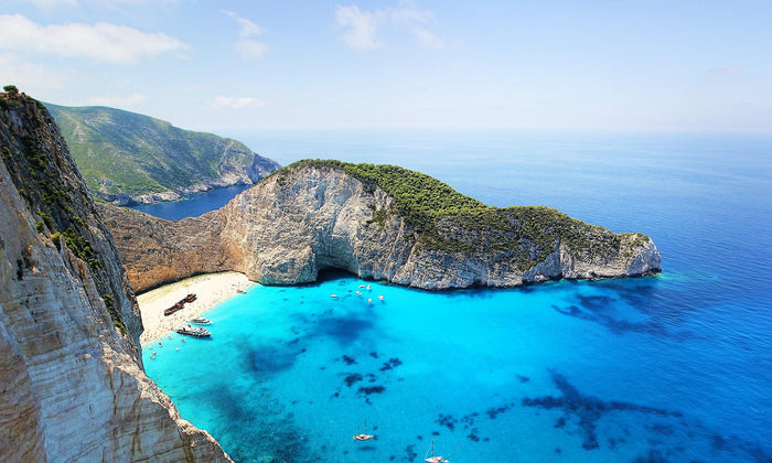 Aerial view of one of the top 10 beaches in Greece with crystal-clear turquoise water, white and pink sand, and dramatic rocky landscapes