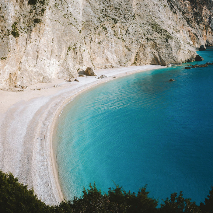 Secluded beach in Southern Europe with crystal-clear water, surrounded by rocky cliffs and untouched nature